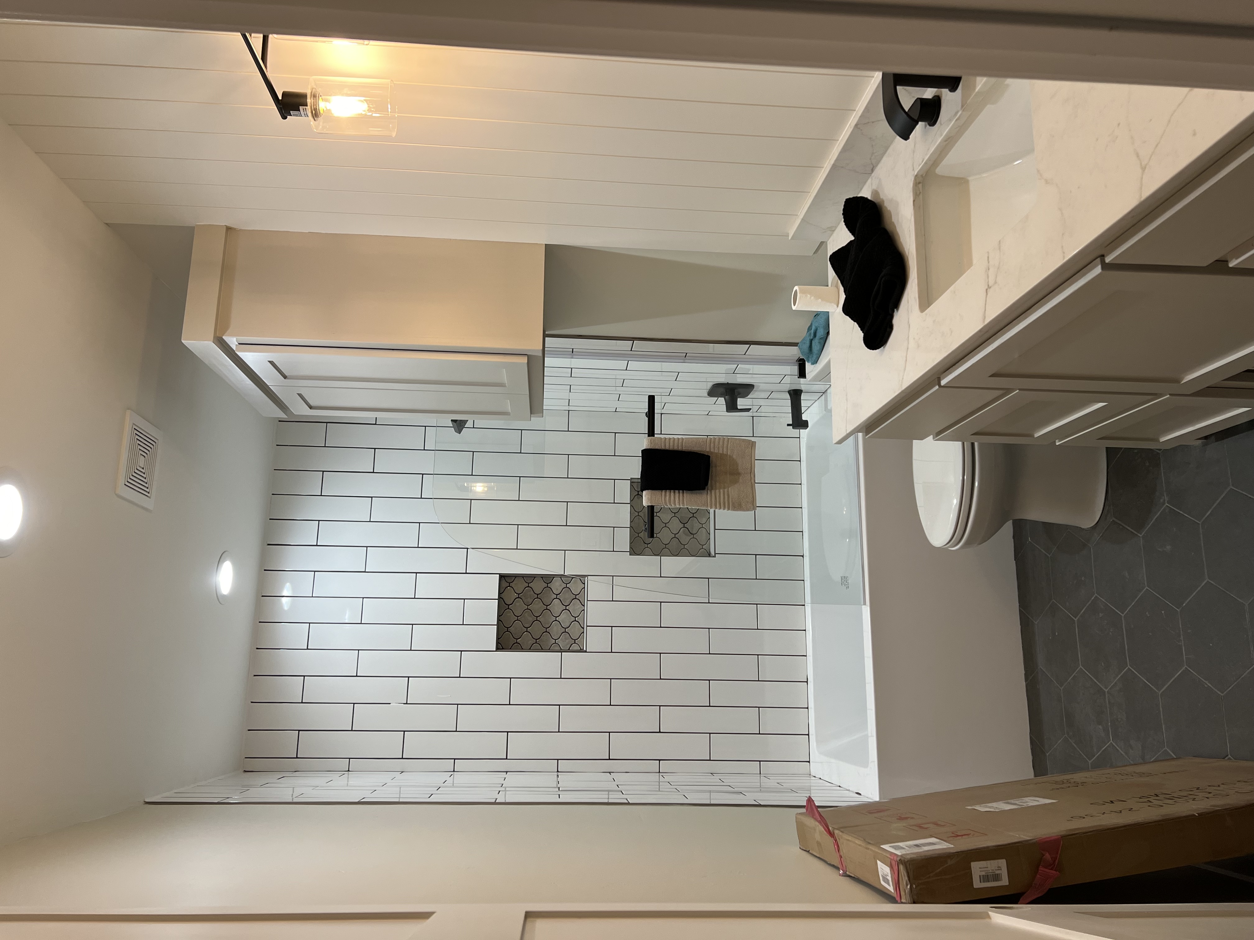 A kitchen with a white tiled wall and a box on the floor